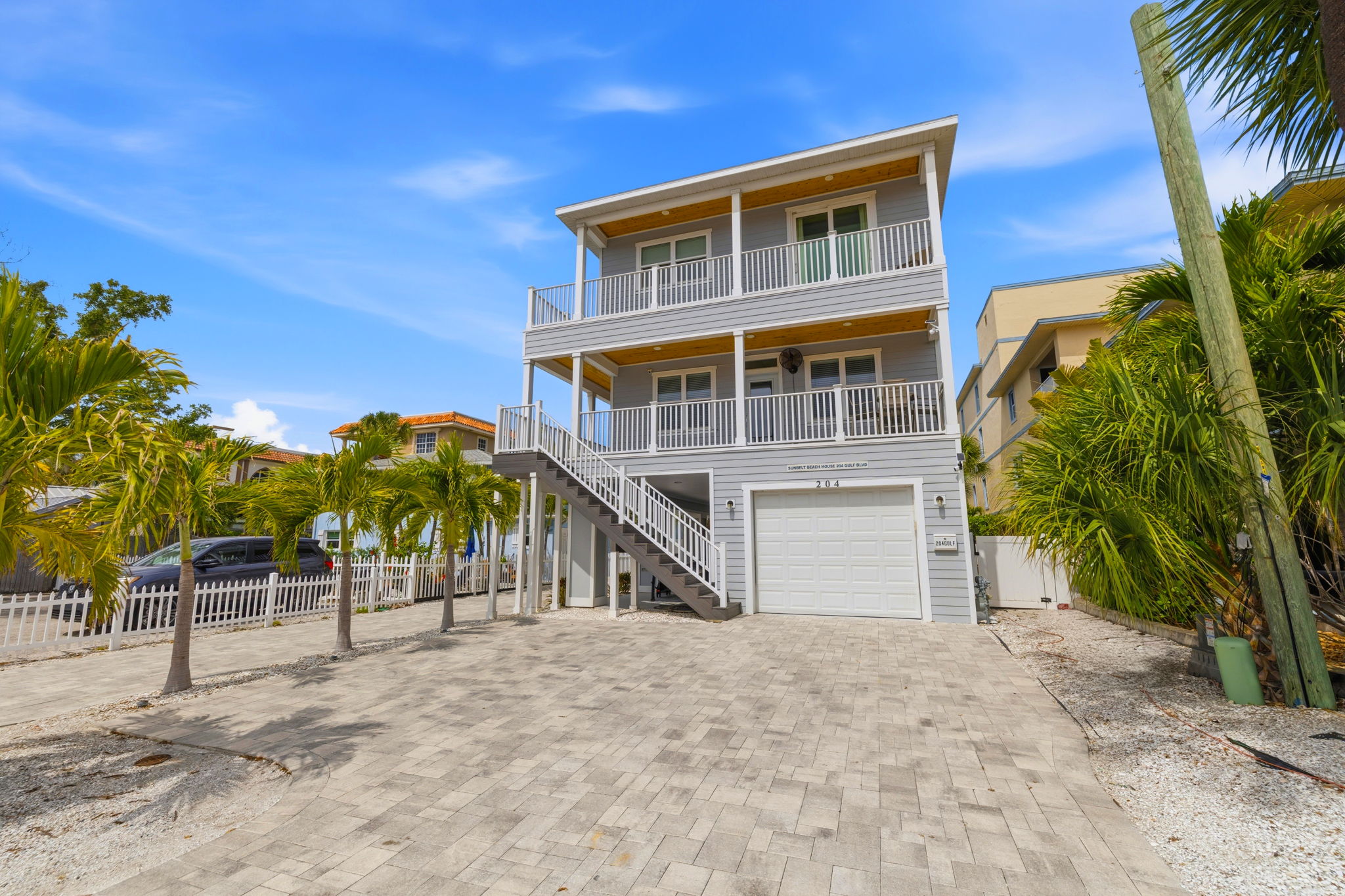 Modern elevated short-term rental investment home on Gulf Boulevard in Indian Rocks Beach Florida showing piling construction ground-level garage and multi-level balconies - elevated newer construction reduces NFIP flood insurance exposure in Pinellas County coastal market