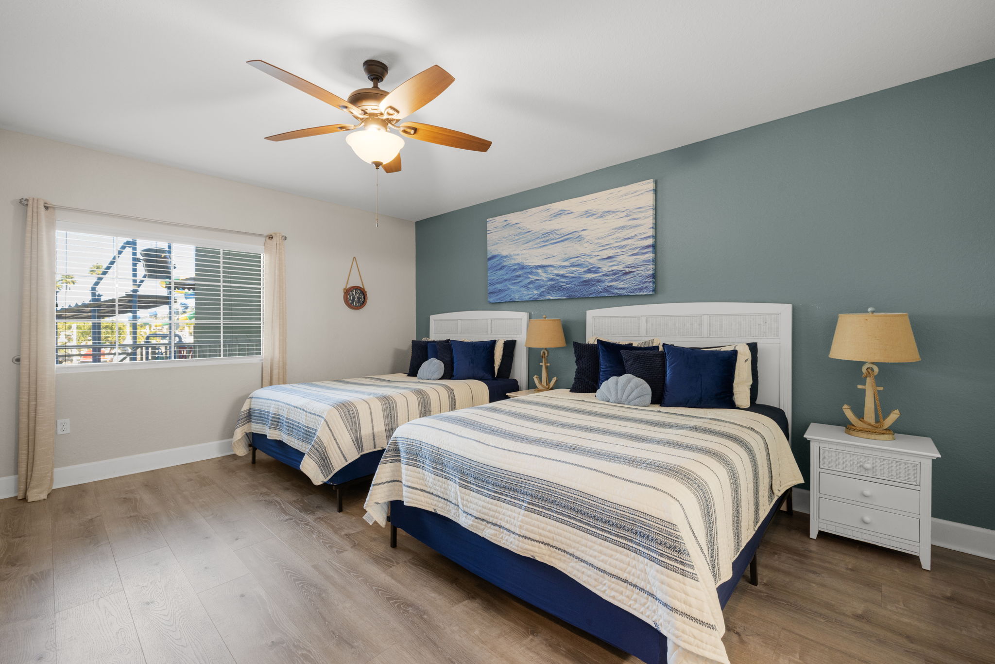 Turnkey coastal furnished bedroom in Indian Rocks Beach STR condo with two beds double occupancy coastal nautical decor white furniture navy blue accents - dual bed configuration maximizes guest capacity and nightly revenue within IRB occupancy limits