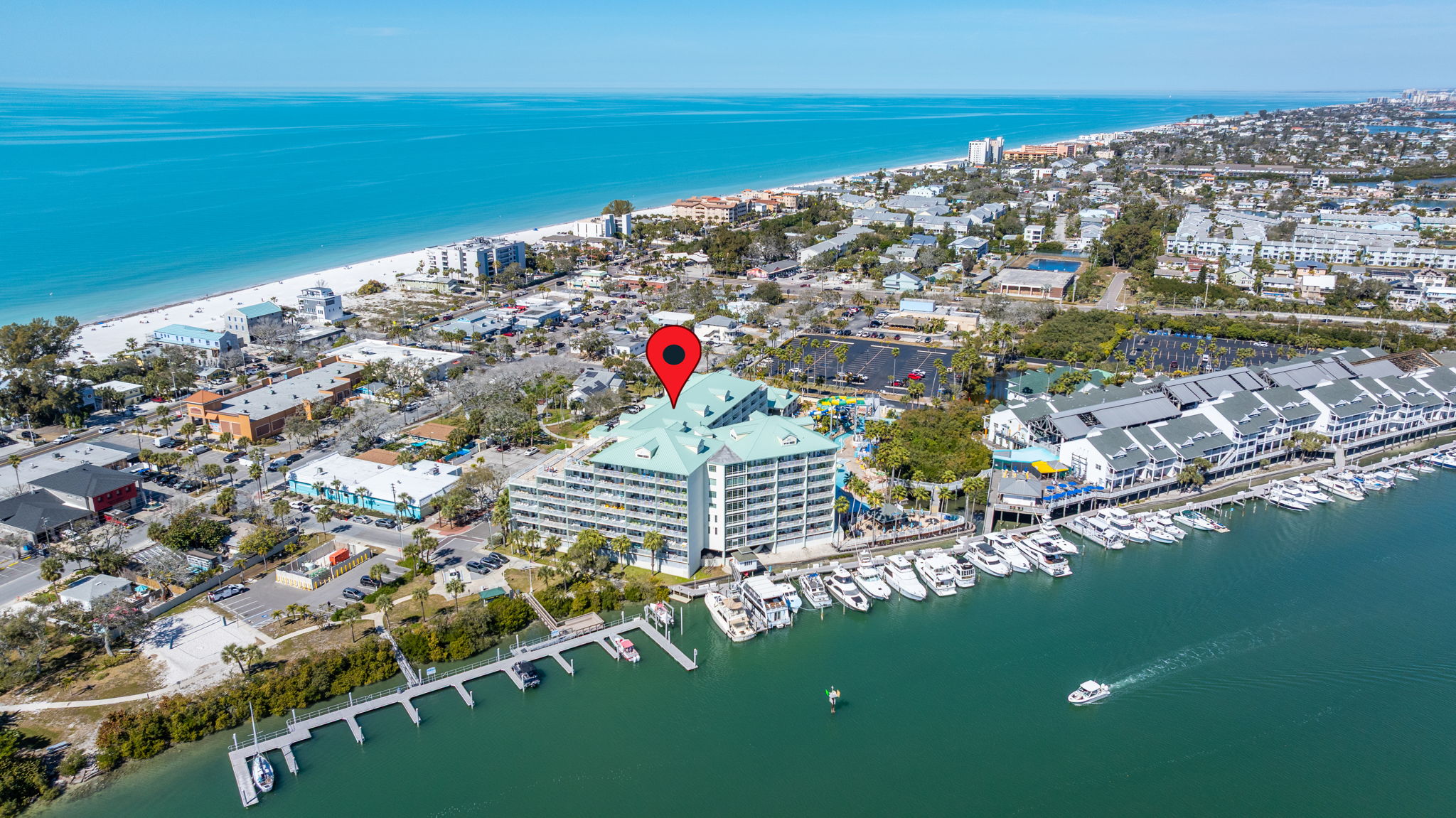 Aerial view of resort-style hotel-condominium in Indian Rocks Beach Florida showing Intracoastal Waterway marina waterfront Gulf of Mexico beach proximity resort pool water park amenities and marina with boats - hotel-condominium STR investment property in Pinellas County