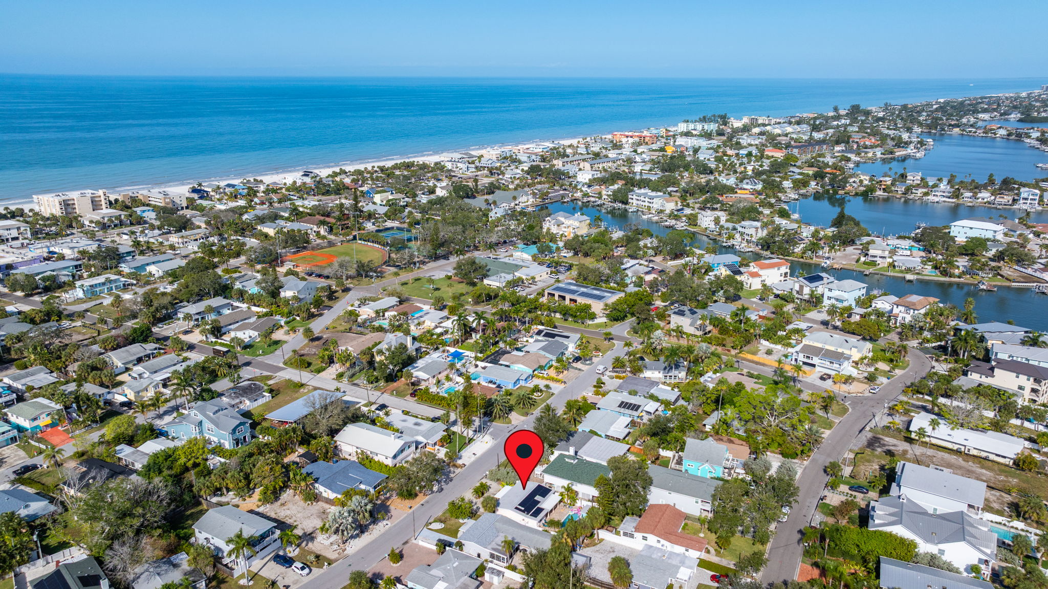 Aerial view of Indian Rocks Beach residential neighborhood showing Gulf of Mexico beach walkable distance from short-term rental investment property with canals and Intracoastal visible - off-water IRB neighborhoods within walking distance of Gulf beach perform strongly as STR investments with right amenity package