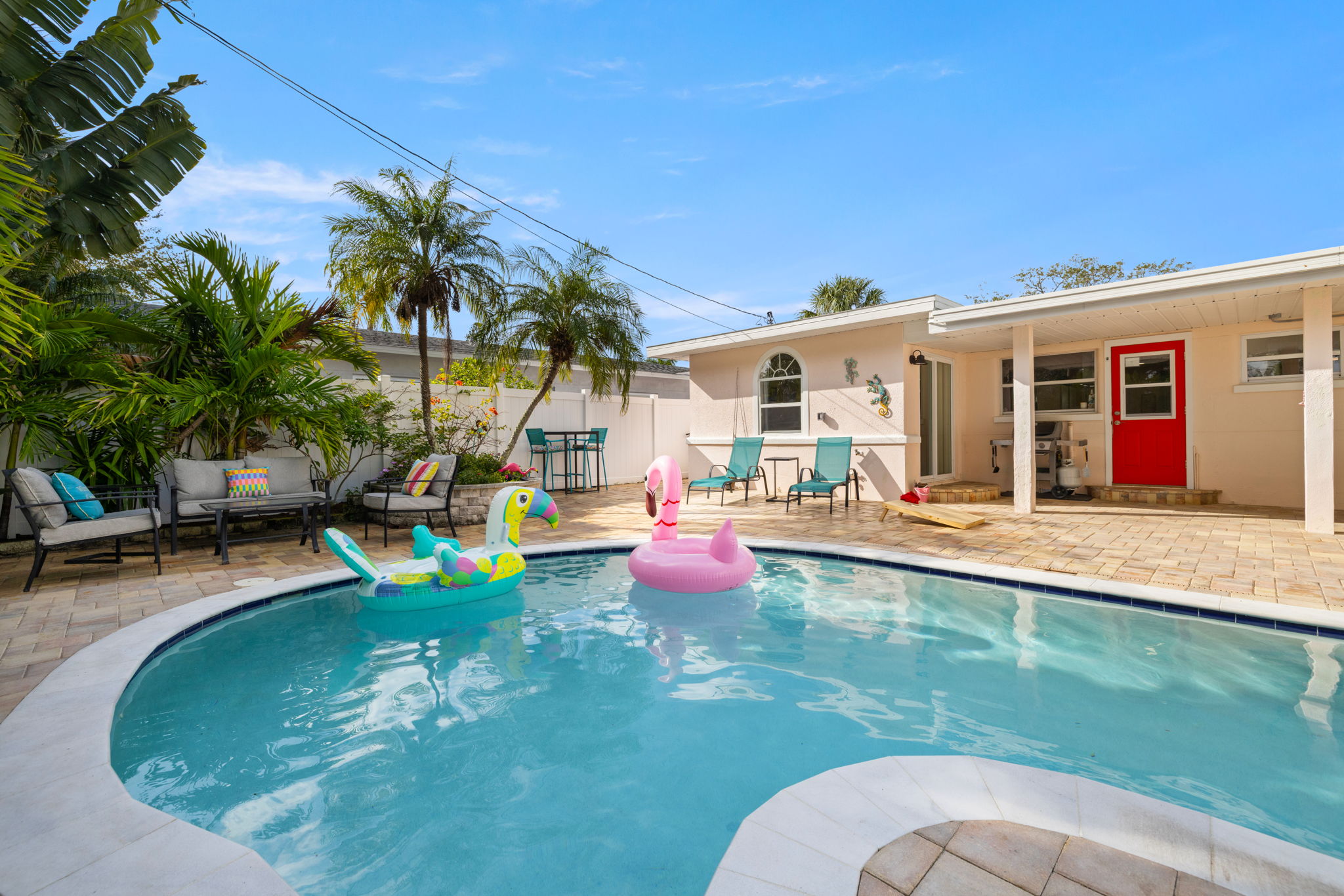Private pool at Indian Rocks Beach short-term rental investment property showing tropical landscaping paver patio lounge chairs and inflatable pool toys - private pool is the single strongest amenity driver for premium nightly rates in the IRB STR market