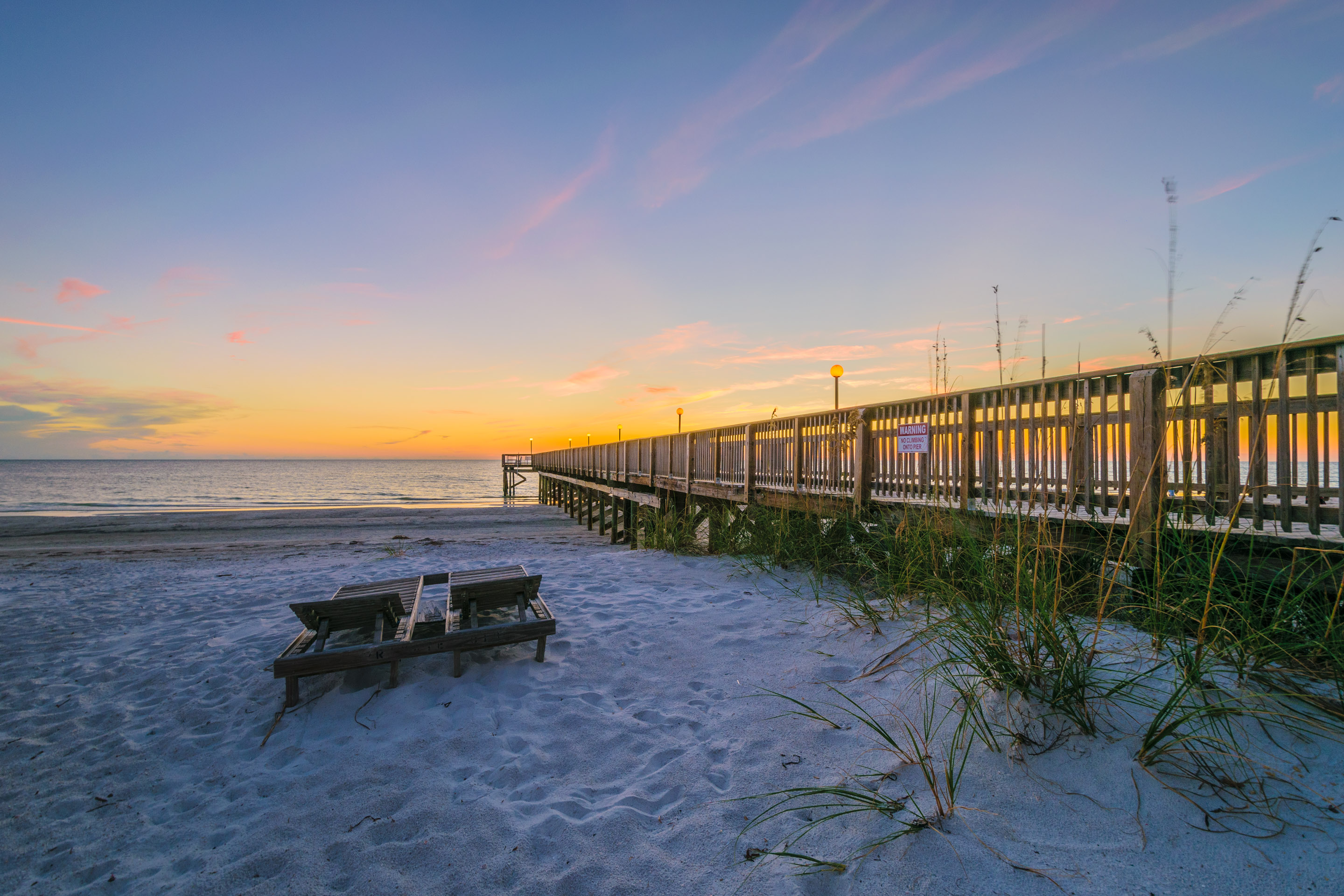 Pier at Beach Cottage condos in Indian Shores Florida at sunset with golden sky reflections on the Gulf of Mexico Gulf-front STR-eligible condo building Pinellas County vacation rental investment