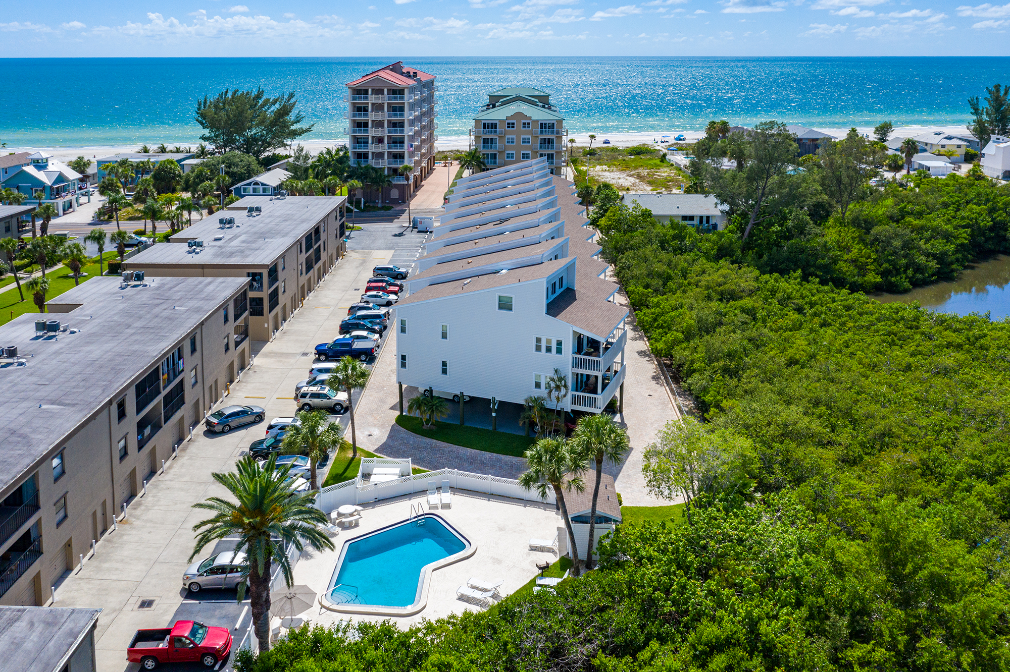 Aerial view of Intracoastal side condo building with pool in Indian Shores Florida showing the Intracoastal Waterway the Gulf of Mexico in the background and pool deck short-term rental investment property Pinellas County