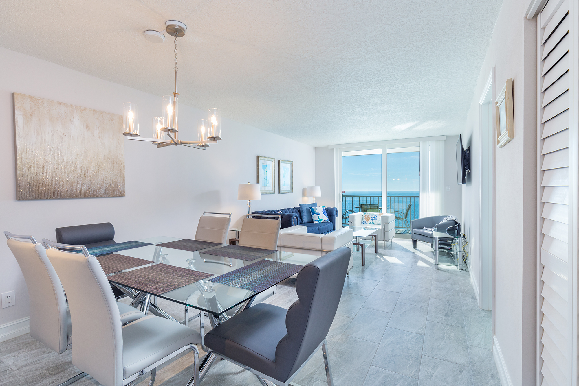 Open plan dining and living room with Gulf of Mexico views through floor-to-ceiling glass doors in Indian Shores Florida vacation rental condo Pinellas County STR investment