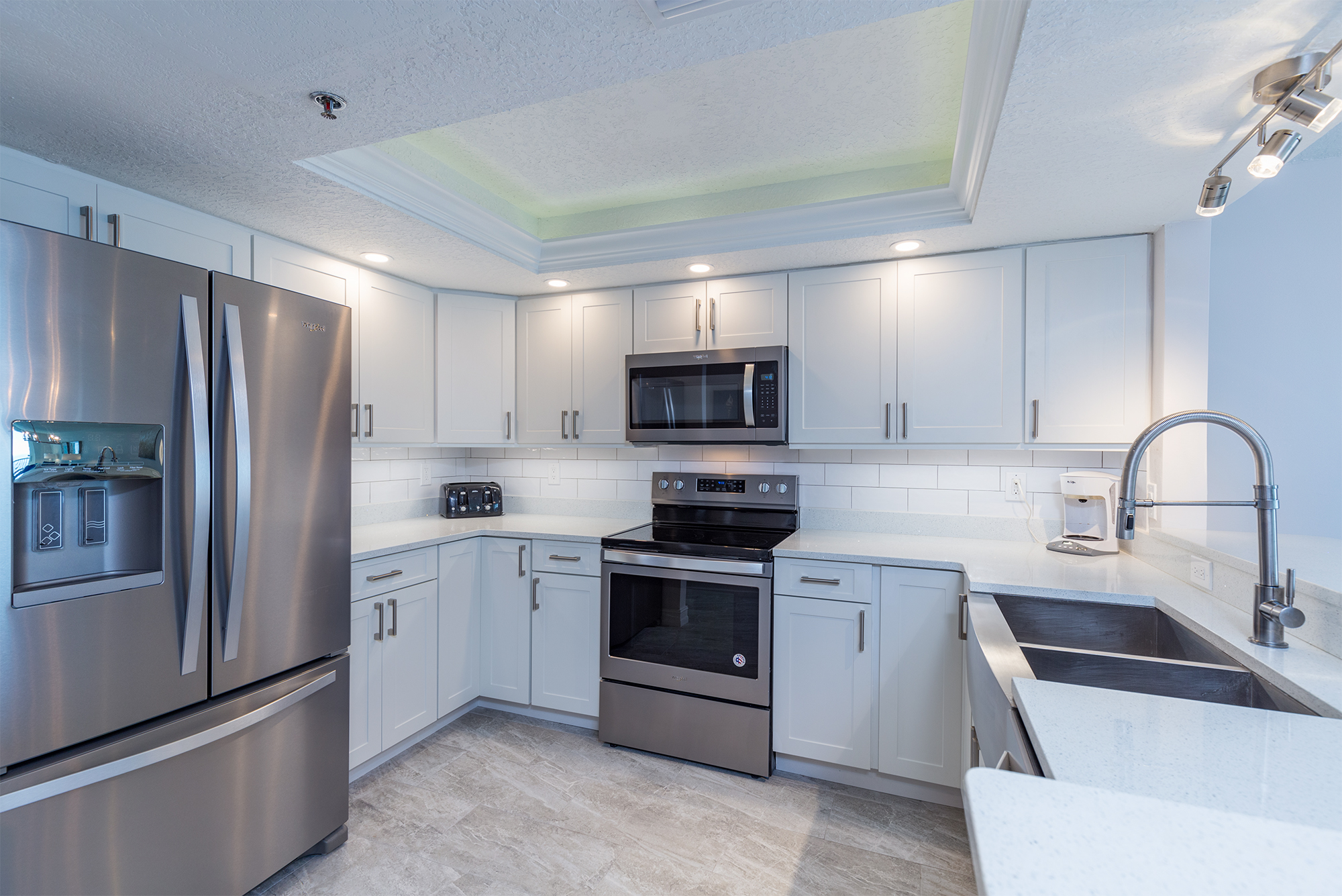 Renovated kitchen in Indian Shores Florida short-term rental vacation rental condo featuring white shaker cabinets quartz countertops stainless steel appliances French door refrigerator electric range microwave fully equipped turnkey investment property Pinellas County Gulf Beaches