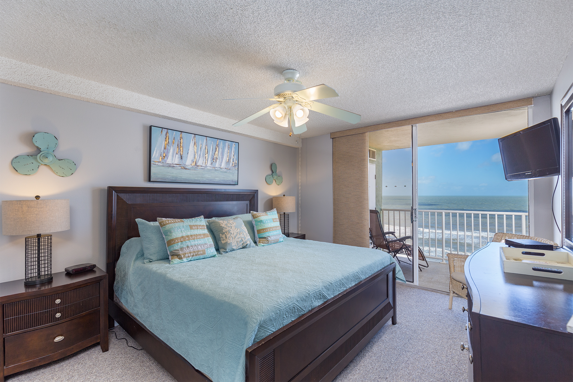 Master bedroom with king bed teal coastal bedding and direct balcony access to Gulf of Mexico ocean views in Indian Shores Florida Gulf-front vacation rental condo short-term rental investment property Pinellas County