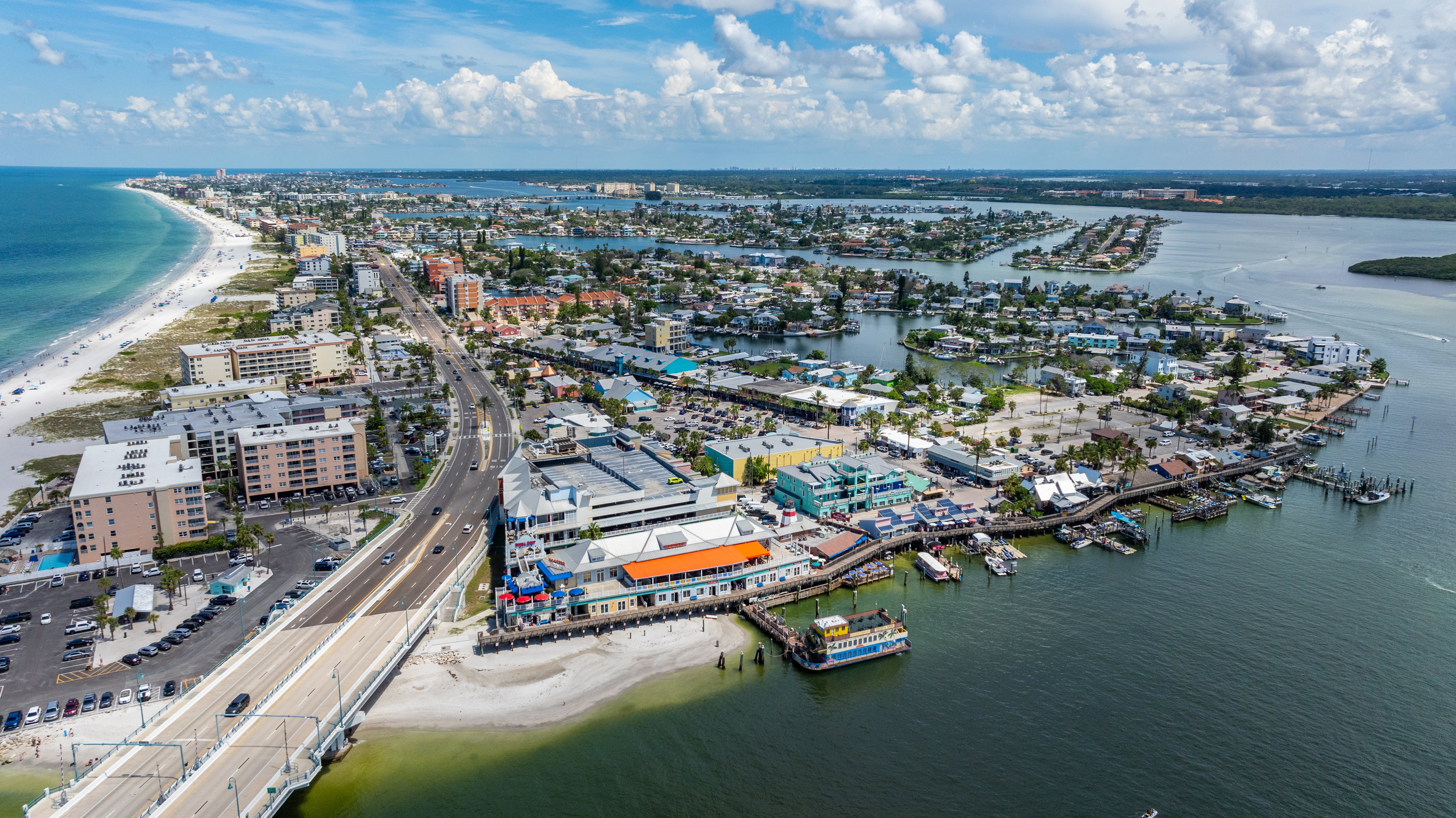 Aerial view looking north from John's Pass Village boardwalk showing Gulf Boulevard vacation rental condo corridor Madeira Beach Florida Pinellas County STR investment properties