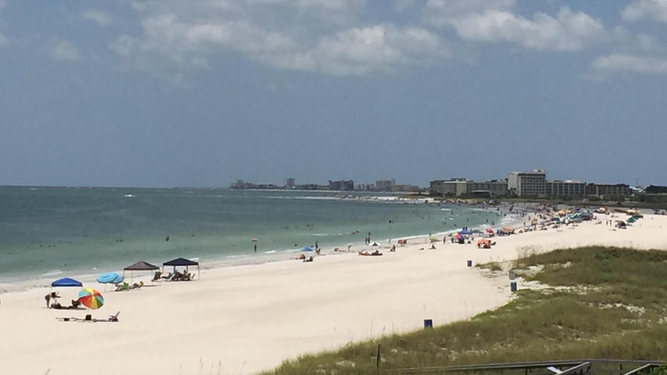 Treasure Island Beach Florida looking north showing the widest beach in Florida up to 1000 feet of white sand Gulf of Mexico shoreline with beachgoers and Gulf Boulevard vacation rental condo corridor in the background Pinellas County STR investment market